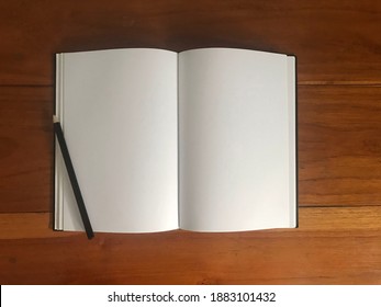 Blank white paper and pencil on wood table in office workplace. Top view with copy space.
