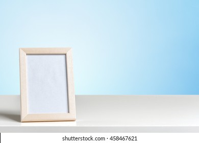 Blank White Picture Frame On The Wall And The Table Wood