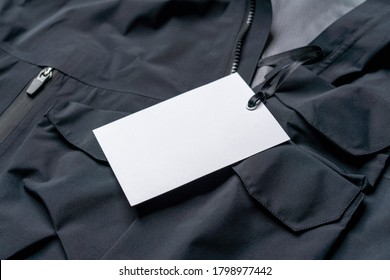 Blank White Rectangular Clothing Tag, Label Mockup Template On Black Stylish Sportswear. Price Tag Label With Copy Space, Empty Space.