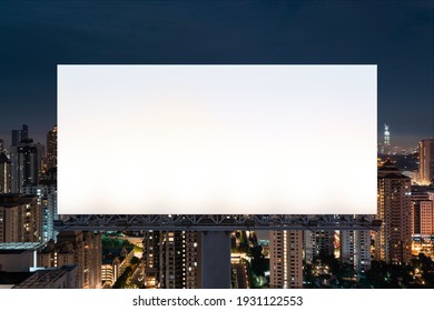 Blank White Road Billboard With KL Cityscape Background At Night Time. Street Advertising Poster, Mock Up, 3D Rendering. Front View. The Concept Of Marketing Communication To Promote Or Sell Idea.