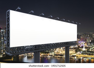 Blank White Road Billboard With Singapore Cityscape Background At Night Time. Street Advertising Poster, Mock Up, 3D Rendering. Side View. The Concept Of Marketing Communication To Sell Idea.