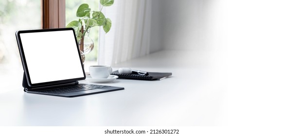 Blank White Screen Tablet With Magic Keyboard In Modern Office Room.