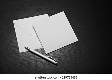 Blank White Square Envelope Letter And White Pen On Black Background. Business Mockup Ready For Corporate Information. 