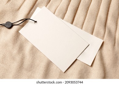 Blank white tags on beige sweater, top view. Space for text - Powered by Shutterstock