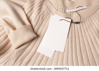 Blank white tags on beige sweater, top view. Space for text - Powered by Shutterstock