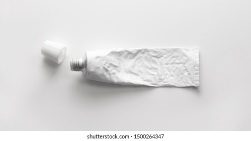 A blank white tube commonly used for pharmaceutical use or chemical products such as ointment, adhesives.
real life used condition. Metal tube. open lid or cap. Isolated on natural white background.