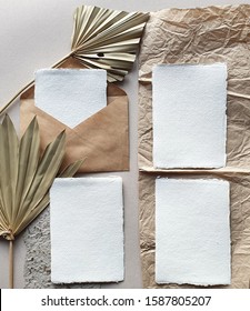 Blank white Wedding invitation cards mockups with dried palm leaf and craft envelope on textured table backgound. Elegant modern template for branding identity. Tropical design. Flat lay, top view