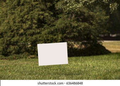 Blank White Yard Sign On A Green Lawn With A Shallow Depth Of Field