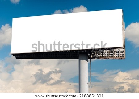 Blank wide white billboard or large display against blue sky with white clouds - mock up. Consumerism, advertising, white screen, template, copy space and mockup concept