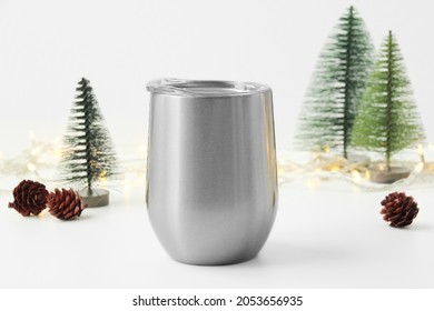 Blank wine tumbler with christmas decor at the background, winter drinkware mock up. Christmas tree, pine cone, warm light.