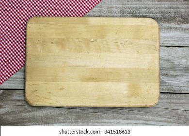 Blank wood cutting board sign with red checkered napkin border on antique rustic wooden background - Powered by Shutterstock
