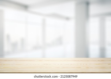 Blank wooden desktop with empty space on modern office interior with large window background, closeup, mock up - Shutterstock ID 2125087949