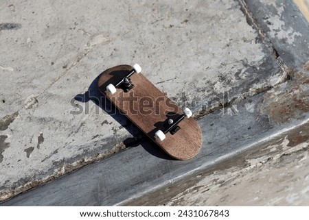 Blank wooden fingerboard at the ramp in skatepark, close up. Mini skateboard, small skateboard deck