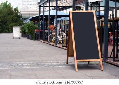 Blank Wooden Sandwich Board Near Outdoor Cafe. Mockup For Design