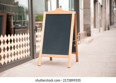 Blank wooden sandwich board near cafe outdoors. Mockup for design