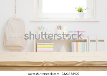 Blank wooden table top on blurred schoolchild room interior background