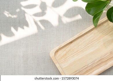 A Blank Wooden Tray Neatly Arranging On Linen Table Cloth, With The Space Show Sunlight And Beautiful Leaves Shadow. Background With Copy Space For Natural And Minimal Products. Soft And Calm Concept