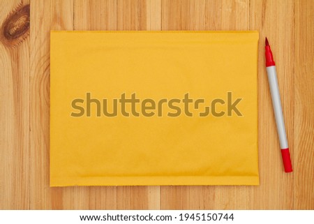 Blank yellow bubble mailing envelope with a marker on wood desk with copy space for your shipping message