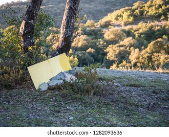 Blank Yellow Sign On The Ground Between Stones And Holm Oak Trunks In A Mediterranean Forest Landscape, For Putting Your Own Text