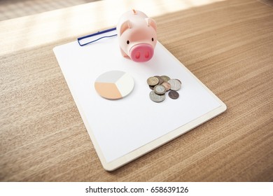 Blank(empty) Clip Board With Pig Coin Bank, Coin, Post It On The Wood Desk.