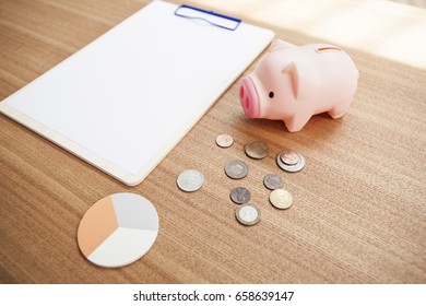 Blank(empty) Clip Board With Pig Coin Bank, Coin, Post It On The Wood Desk.