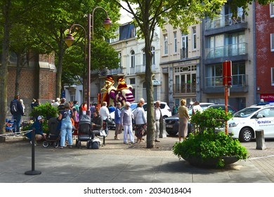 Blankenberge,  Belgium - August 29, 2021: Parade Float Hannibal Elephant Flowers Riding Through The Streets. Tourists Looking From The Footpath And Square. 2 Mothers With Pram Sitting On Garden Bench.