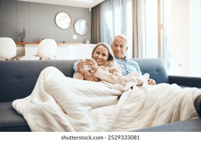 Blanket, coffee and mature couple on sofa in living room of home together for bonding, break or romance. Cozy, cuddle or hug with happy man and woman in apartment for love, relationship or drink - Powered by Shutterstock