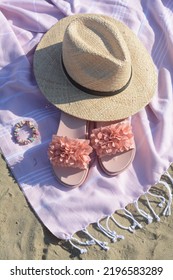 Blanket With Stylish Slippers And Straw Hat On Sandy Beach, Above View