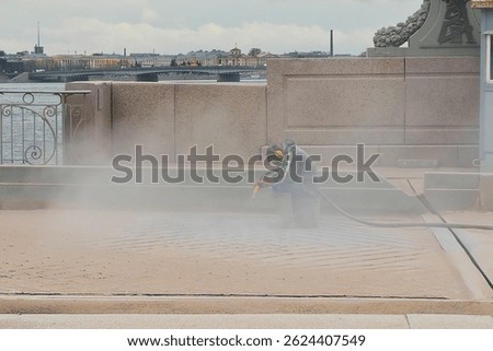 Blast cleaning. An unrecognizable man at work at the bridge construction site, working in the dust. The dusty construction that floats in the air.