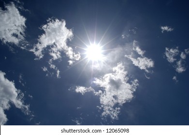 Blazing Hot Sun Shining In Blue Sky With Clouds