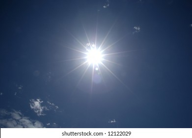 Blazing Hot Sun Shining In Blue Sky With Clouds