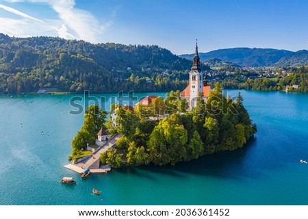 Bled, Slovenia - Aerial view of beautiful Pilgrimage Church of the Assumption of Maria on a small island at Lake Bled and lots of Pletna boats on the lake at summer time