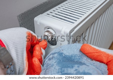 Bleed air valve in heating radiator at home. Adjust heating system, preparing the house for the new cold winter season. Hand with a key for draining air drains water and air from the heater.