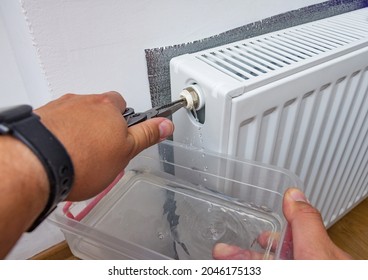 Bleed valve in central heating radiator. Hand draining air for adjusts heating system at home. Preparing the house for the new cold winter season.