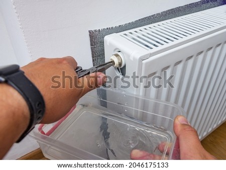 Bleed valve in central heating radiator. Hand draining air for adjusts heating system at home. Preparing the house for the new cold winter season.