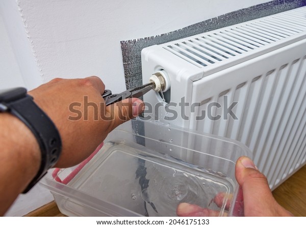 Bleed valve in central heating radiator. Hand\
draining air for adjusts heating system at home. Preparing the\
house for the new cold winter\
season.