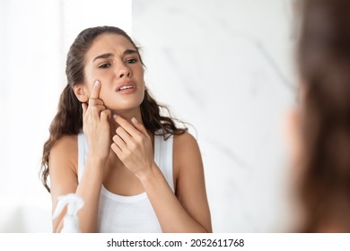 Blemish-Prone Skin And Acne. Desperate Lady Squeezing Pimple On Face Standing Near Mirror In Modern Bathroom At Home. Facial Skincare, Health Issues Concept. Selective Focus - Shutterstock ID 2052611768