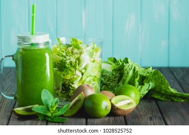 Blended green smoothie with ingredients on wooden table selective focus. Blue background. - Shutterstock ID 1028525752