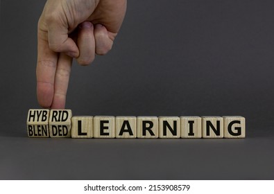 Blended or hybrid learning symbol. Businessman turns cubes, changes words blended learning to hybrid learning. Grey background. Business, education and blended or hybrid learning concept. Copy space.