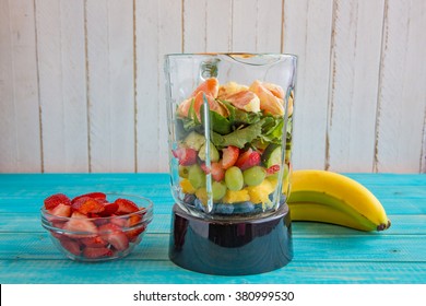 Blender Filled With Organic Fruits and Vegetables Including Oranges, Spinach, Cucumbers, Strawberries, Grapes, Pineapple, and Bananas for a Healthy Smoothie - Powered by Shutterstock