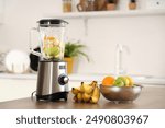 Blender with fruits for tasty smoothie on table in kitchen