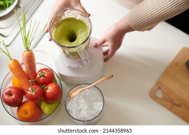 Blender With Green Smoothie, Bowl Of Ice And Bowl Of Fresh Vegtable On Kitchen Table Of Woman