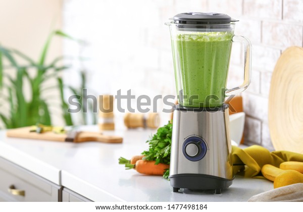Blender with healthy smoothie and ingredients on
table in kitchen