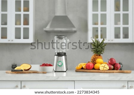 Blender and smoothie ingredients on white marble countertop in kitchen