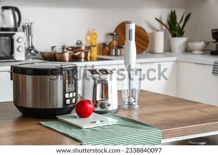 Blender, toaster, multi cooker and apple on wooden table in kitchen