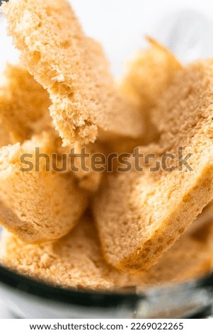 Blending stale bread in a blender to make bread crumbs.