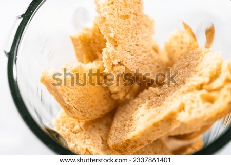 Blending stale bread in a blender to make bread crumbs.