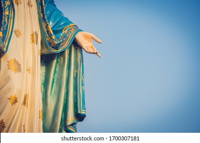 The Blessed Virgin Mary Statue Figure. Catholic Praying For Our Lady - The Virgin Mary. Blue Sky Copy Space On Background. Hand Closed-up