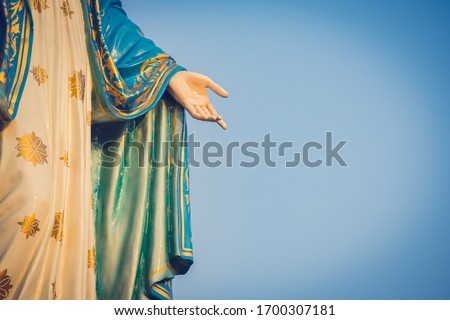 The blessed Virgin Mary statue figure. Catholic praying for our lady - The Virgin Mary. Blue sky copy space on background. Hand closed-up
