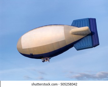 Blimp With A Pilot On The Background Of Blue Sky. 